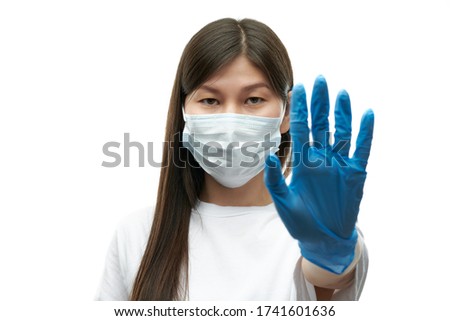 Young asian girl in medical mask and blue gloves show stop sign on white background isolated