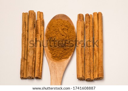 Close-up view of cinnamon sticks and powder on white background.