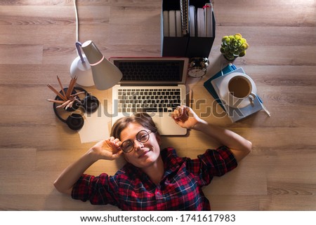 Happy woman is lying on floor and working on computer remotely at home. Businesswoman working online during the quarantine. Self isolation. Networking. Online education. Coronavirus. Top view