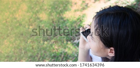 Top corner image close up young woman Asian is calling phone at the green the park.