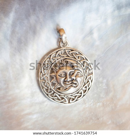 Sterling siver pendant in the shape of sun and moon on white shell background