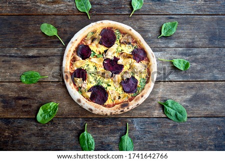 Unique pizza picture with basil leaves around the vegetarian pizza on the old wooden table