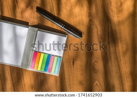 colorful small notepad, pen and sunlight table