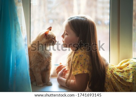 Happy twins with redhead cat at window in cozy home