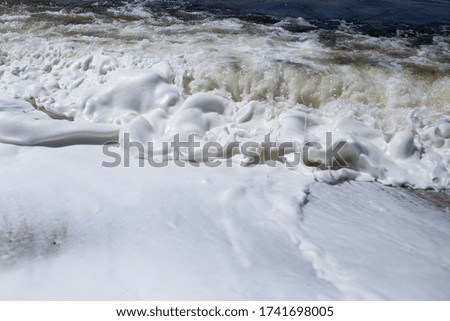 River bank, clear water and white thick foam from the surf.