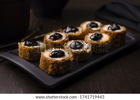 Traditional salmon fish hot roll with tare sauce in a black platter in wood background Royalty-Free Stock Photo #1741719443