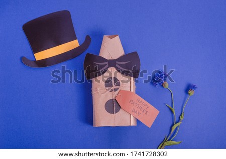 Father's day concept. Happy father's day. Gift box in the form of a shirt on a blue background with flowers with copy space.