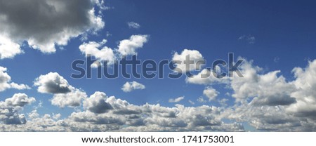 A series of clouds swims across the blue sky
