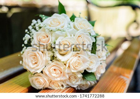 Beautiful wedding bouquet of orange roses on a wooden bench