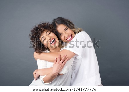 Happy bright positive moments of two stylish girls hugging each other and smiling. Closeup portrait funny joyful attractive young women having fun, lovely moments, best friends.