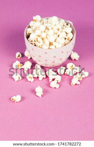 Fresh popcorn in a white pink bowl on pink background
