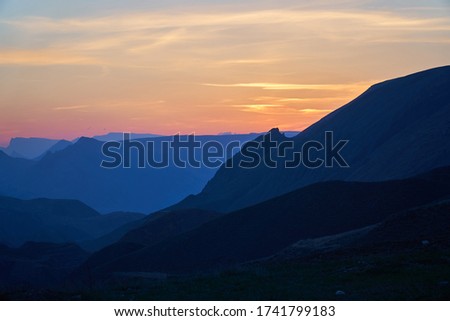 Sky and birds. Sunset, dawn, and clouds. The sun is burning with bright rays. behind the mountains.