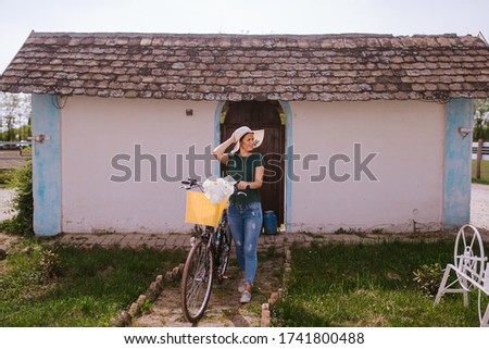 A beautiful young caucasian woman with a straw hat next to a bicycle with flowers in a basket