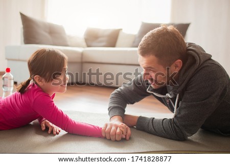 father and daughter are training at home. Workout in the apartment. Sports at home. Compete in arm wrestling and lie on a yoga mat.