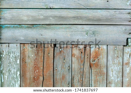 the wall is made of horizontal and vertical wooden planks, nailed, with peeling green paint, cracks and craquelure and defects.