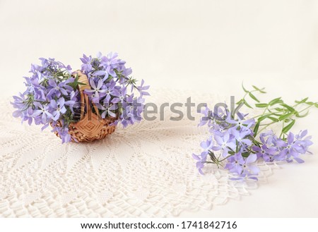 A bouquet of delicate pastel flowers in a basket on an openwork napkin, side view, white background