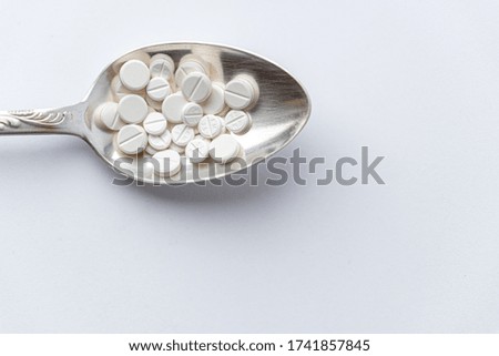 Medicine and health, treatment, pharmacy, coronavirus, pandemic, epidemic concept - layout one silver big tablespoon with different pills and capsules on a white background copy space.