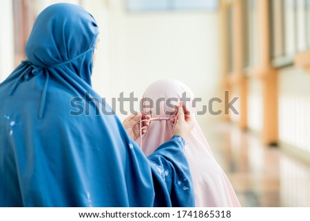 Concept Eid mubarak, Muslim girl, Islamic girl, teasing mother with love and mother watching beautiful hijab at mosque after prayer.