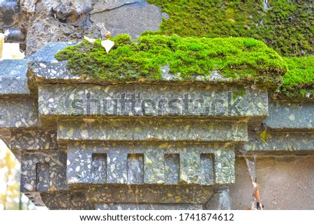 Detail of top of abandoned old weathered column with covered green moss. Photo of historical architecture