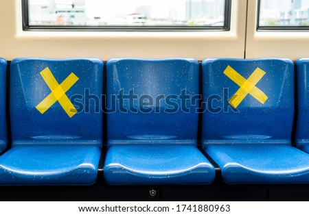 Seating on a public transportation in Bangkok marked with a yellow crossed sign to prohibit people from sitting next to one another following social distancing protocol during the Covid-19 pandemic. Royalty-Free Stock Photo #1741880963