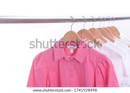  pink shirt and white T-shirt with long sleeved white shirts on wooden clothes rack isolated over white
