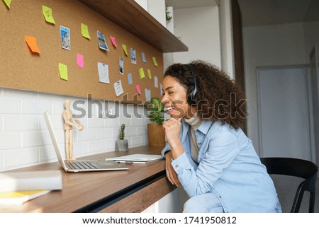 Happy african american teen girl student worker wear headphones video conference calling online on laptop computer laughing at home office. Elearning zoom app video call, distance videoconference. Royalty-Free Stock Photo #1741950812