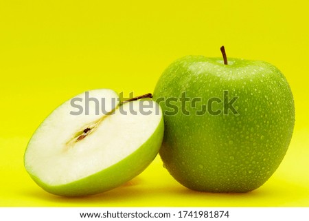 One and a half green apples with water droplets
