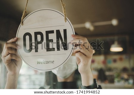 Open. barista, waitress woman wearing protection face mask turning open sign board on glass door in modern cafe coffee shop, cafe restaurant, retail store, small business owner, food and drink concept Royalty-Free Stock Photo #1741994852