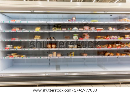 Half empty supermarket shelves with chilled smoked meat delicacies. Popular unhealthy food. Blurred. Front view.