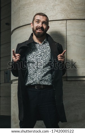 Happy bearded businessman after successful deal playing the fool outside his office building.