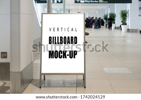 Mock up blank indoor vertical signboard with clipping path on stainless steel stand on walkway in airport terminal, empty space for insert advertising or announcement information