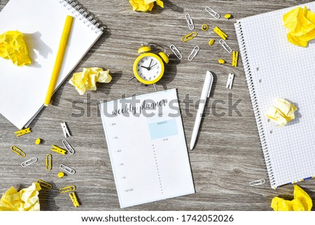 Weekly planner with alarm clock and office supplies. Business planning, workplace. paper
