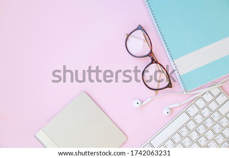 pink office desk with smartphone with blank screen mockup, laptop computer, cup of coffee and glasses of supplies. Top view with copy space, flat lay.