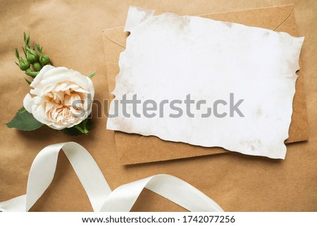 postcard mockup. minimalistic design. white rose and envelope on a craft background. invitation. congratulation
