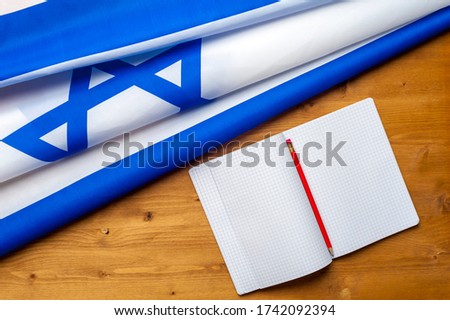 Top view of the flag of Israel lies on a wooden table next to a notepad and trail. Law concept in Israel. Advertising space