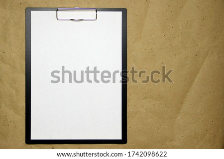 A tablet with a white sheet of A4 format on a beige craft paper. Concept of new opportunities, ideas, undertakings, innovations. Stock photo with empty place for your text and design.