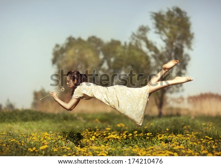 Girl in pajamas night flying over the field and smelling dandelions. Royalty-Free Stock Photo #174210476