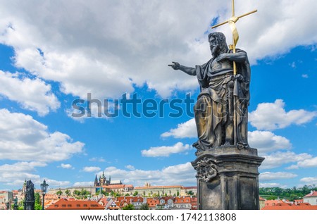 Saint John the Baptist statue on Charles Bridge Karluv Most over Vltava river with Prague Castle, St. Vitus Cathedral in Hradcany district, blue sky white clouds background, Bohemia, Czech Republic Royalty-Free Stock Photo #1742113808