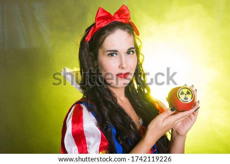Woman wearing a fairy tale dress holding an apple with radiation symbol. Environmental problems concept, radioactive disaster as danger on nature.