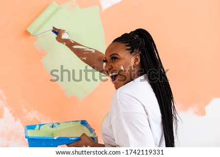 Pretty young african american woman with painting roller indoors. Redecoration, renovation, apartment repair and refreshment concept. Royalty-Free Stock Photo #1742119331
