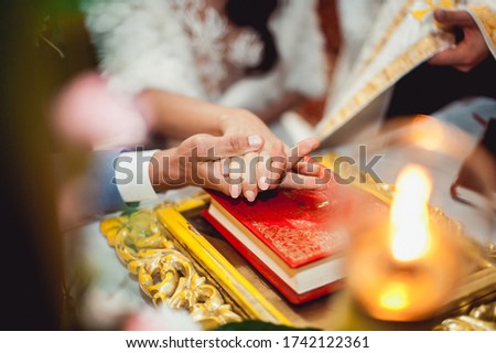 Bride and groom putting their hands on an old bible give a vow in church, close up.
