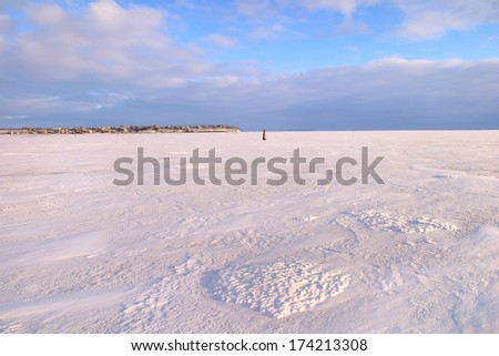 amazing winter landscape beneath the ice of a broad river and beautiful clouds in the blue sky