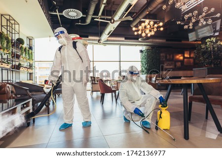 Professional workers in hazmat suits disinfecting indoor of cafe or restaurant, pandemic health risk, coronavirus Royalty-Free Stock Photo #1742136977