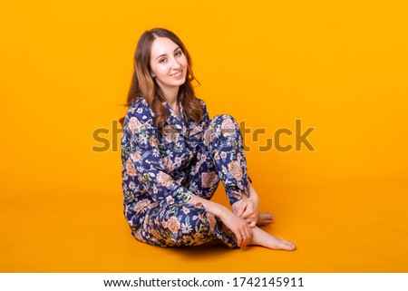 Excited young woman in home wear, widely smiling having fun. Isolated on yellow background.