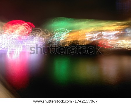 Abstract lights in the night life district reflected against the calm water of the river. 
