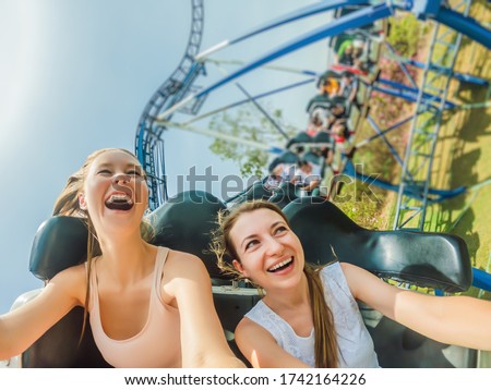 Two happy girls having fun on rollercoaster Royalty-Free Stock Photo #1742164226