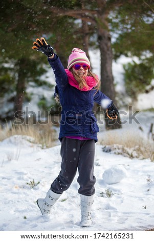 Little girl throwing snowball on the mountain
