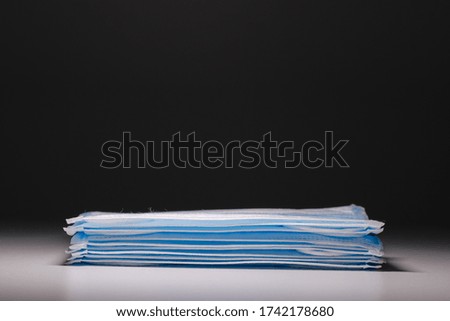 A stack of surgical mask with spotlight effect in isolated black background. New mask.