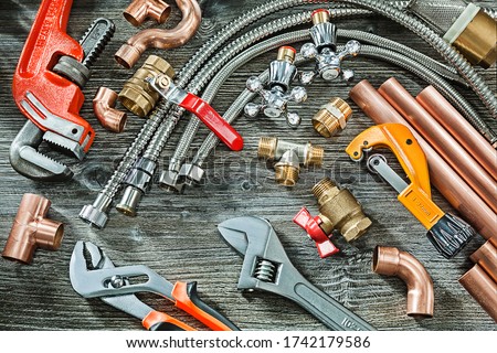 plumbing concept big set of piping accessories monkey and plumb adjustable wrenches copper brass fittings pipe cutter on vintage wood background Royalty-Free Stock Photo #1742179586