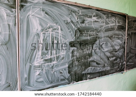 Photo of a dirty school board with mathematical formulas on it, in a school.